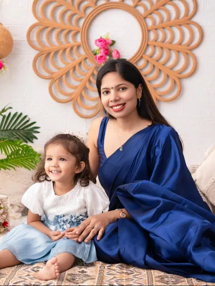 A serene mother and daughter portrait. The mother's elegant blue saree complements the daughter's dress, creating a beautiful and coordinated look.