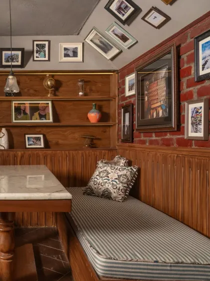 The grooved wooden wainscoting and exposed brick wall provide a rich textural backdrop for this intimate booth. The space is designed to feel like a private alcove, perfect for escaping the hustle of the city.