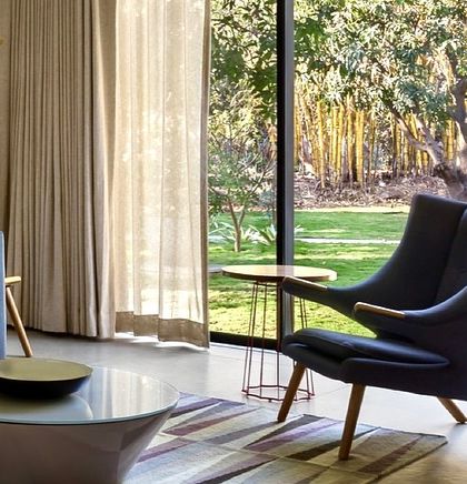 A close-up of the seating area in the Mango Orchard House den, where a modern armchair is perfectly positioned to enjoy the garden view.