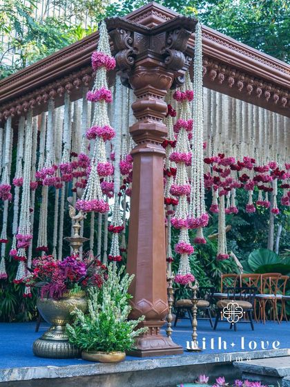 A corner of the summer wedding mandap, showcasing the carved pillar and cascading floral garlands.