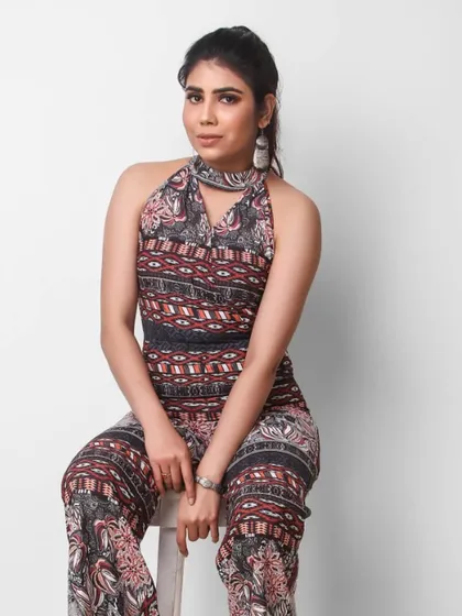 A seated portrait of a model in a patterned jumpsuit. This is a standard full-body shot that every portfolio needs.