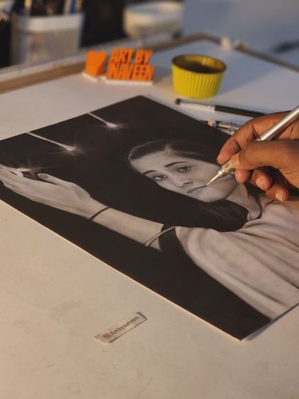 A shot of me working on the sparkler portrait, using a fine-tipped tool to create the bright sparks against the dark charcoal background.