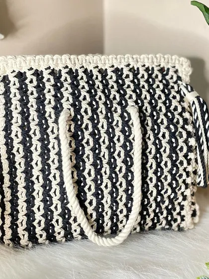 A classic that never goes out of style. This black and white macrame tote bag is spacious enough for all your essentials, featuring a thick, comfortable handle and a playful matching tassel.