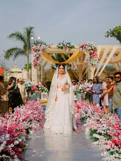 The bride's grand entrance down an aisle lined with pink and white flowers, a truly spectacular moment.