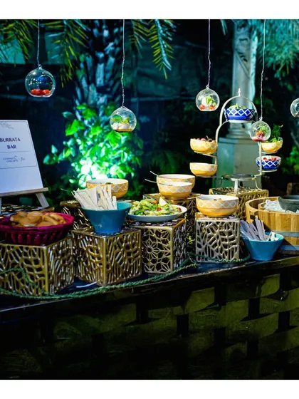 A beautifully styled Burrata Bar, complete with hanging glass terrariums containing fresh ingredients. This innovative concept allows guests to customize their own burrata salads for a fresh and interactive experience.