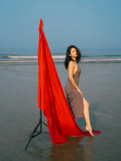 A powerful, full-length fashion shot. The flowing red fabric creates a strong visual line that draws the eye across the frame.