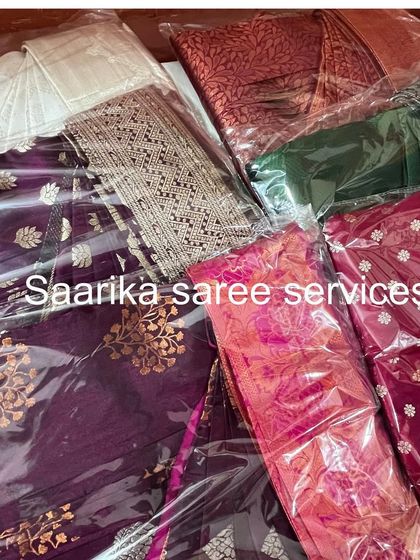A collection of sarees, including some beautiful purples and reds, all packed and ready for a customer.