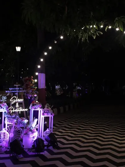 A modern Sangeet entrance with a black and white chevron floor and arches of bulb lights. This design creates a chic and dramatic pathway, setting the tone for a stylish party.