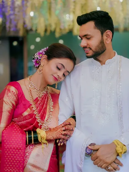 A moment of quiet comfort as the bride rests her head on her partner's shoulder. Her beautiful pink saree and traditional jewelry shine in this heartfelt portrait.
