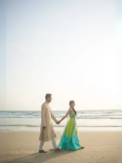 A full-length shot of a couple walking on the beach, capturing the serene environment and their relaxed connection.