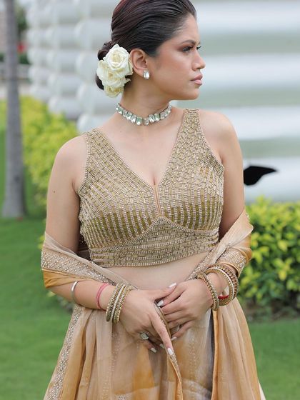 A model in a chic beige lehenga with a woven gold blouse, paired with a simple diamond choker. A very elegant and understated look.