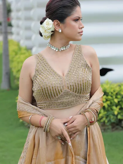 A close-up of the gold lehenga's blouse, showing the intricate beadwork and the delicate choker necklace.