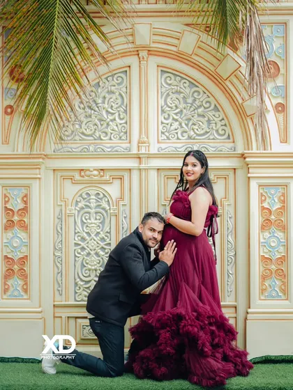 A classic maternity pose with the father-to-be kneeling by the baby bump, set against a grand, elegant doorway.