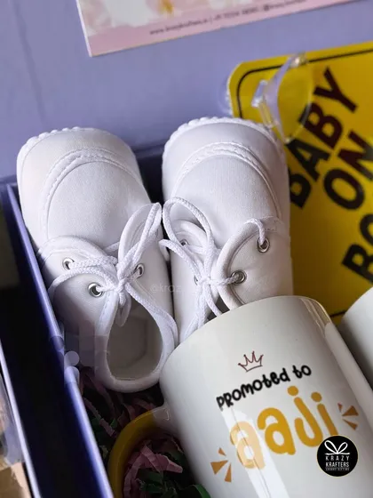The tiny white baby shoes are a classic and powerful symbol of the new life on the way, making them a perfect centerpiece for any announcement.