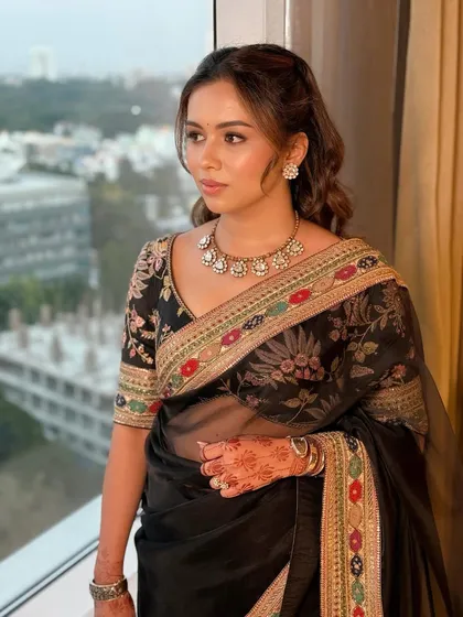 This client is the picture of timeless luxury in a classic black Sabyasachi saree. I created a soft glam look with dewy, glowing skin and gentle waves in her hair to complement the intricate floral embroidery of her outfit, perfect for an elegant evening affair.