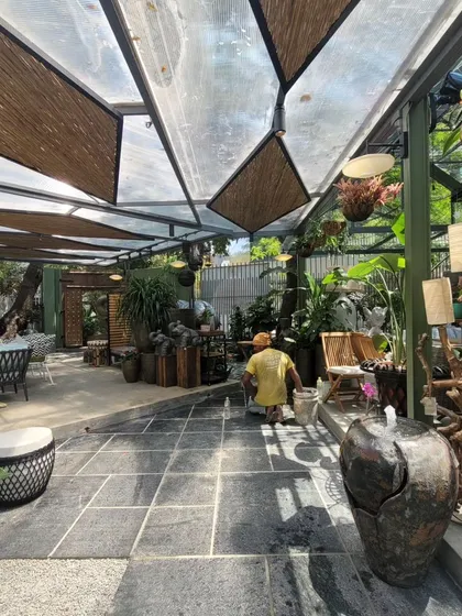 The flooring of black stone pavers and the semi-covered roof create a comfortable, all-weather space for browsing. A variety of planters, furniture, and water features are carefully arranged to create distinct zones.