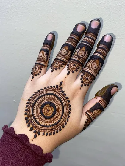 This back-of-hand mandala is simple yet so elegant. The design focuses on a single, beautifully detailed circle with matching patterns on the fingers.