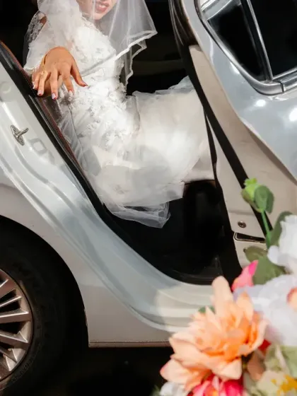 A detail shot of hands helping the bride as she steps out of the wedding car.