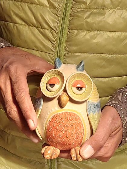 A close-up of a customer holding one of my sleepy-eyed owl figurines. The textured details on the chest and the expressive eyes are what give each piece its unique character.