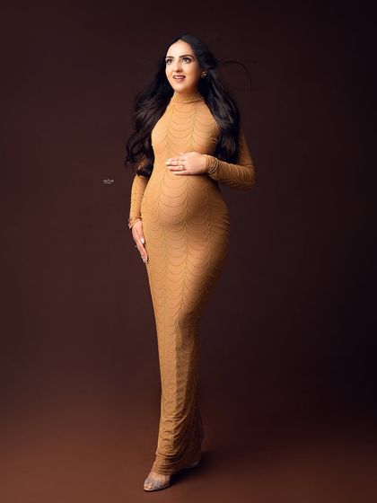 A full-length shot of this gorgeous mamma in a form-fitting, long-sleeved beige dress. The wind in her hair adds a beautiful, dynamic element.