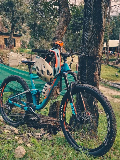 A full-suspension Giant mountain bike taking a rest against a tree. We believe in using quality gear that can handle the tough Himalayan trails.