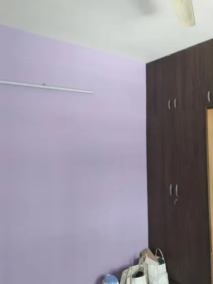 This bedroom wardrobe and integrated dressing table feature a dark wood finish that contrasts beautifully with the light purple wall paint.