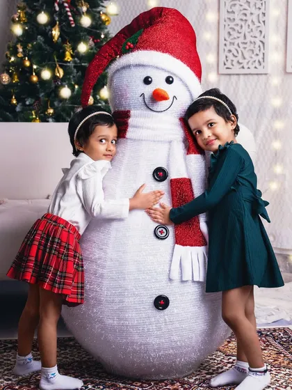Twin girls give our friendly studio snowman a big hug, their matching outfits adding to the cuteness.