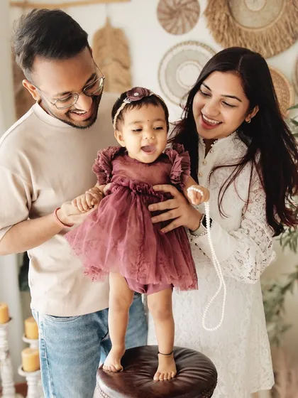 A candid moment of joy during a first birthday session. The genuine smiles and laughter as they play with their daughter are what make these family photos so special.