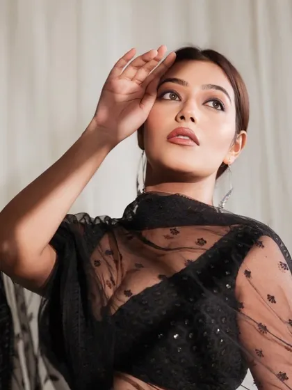 A close-up, artistic shot focusing on the model's expressive upward gaze, with the sheer black dupatta adding texture.