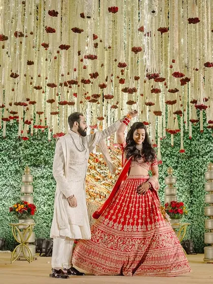 The couple shares a dance on the stage, showcasing the grand scale of the floral installation.
