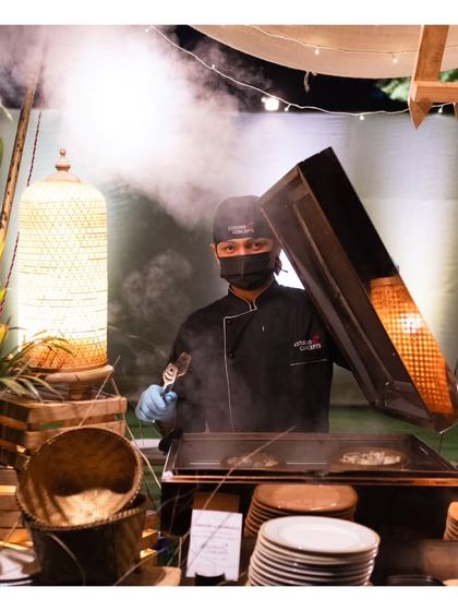 A chef creates a dramatic steam effect while cooking at a live station. This kind of culinary showmanship is part of the unique and memorable experience we provide.