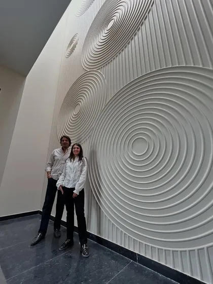 Posing in front of the dramatic, double-height wall with a concentric circle design at the 'House of Passages'. This feature turns a simple corridor into a work of art.
