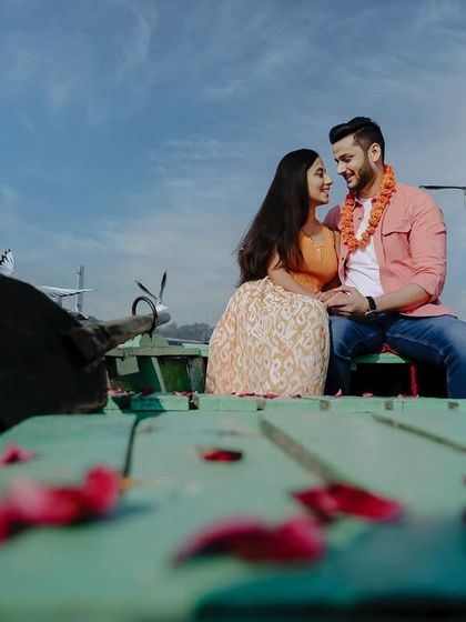 A classic Bollywood-style pre-wedding shot on a boat at Yamuna Ghat, with birds flying around the happy couple.