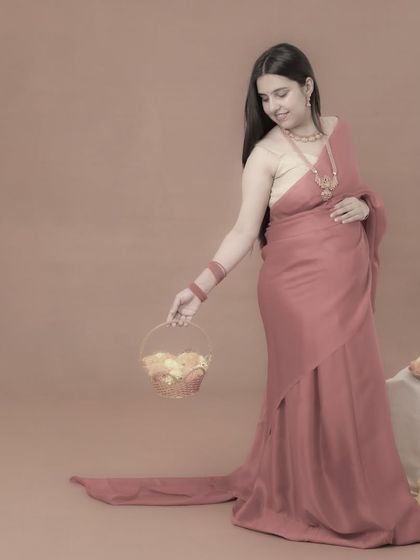 A simple and elegant portrait of a mom-to-be in a pink saree, holding a basket of flowers. The soft, monochromatic edit gives this traditional photo a timeless and artistic feel.