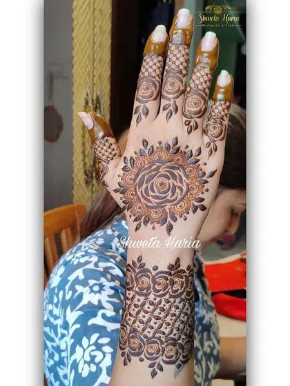 A lovely floral mandala design on the back of the hand. The central rose mandala is paired with a wristband of repeating rose patterns, creating a cohesive and beautiful floral theme.