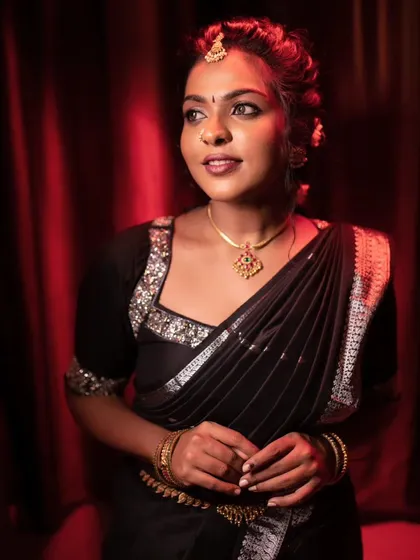 A model posing in a black saree, with a confident and bold expression.
