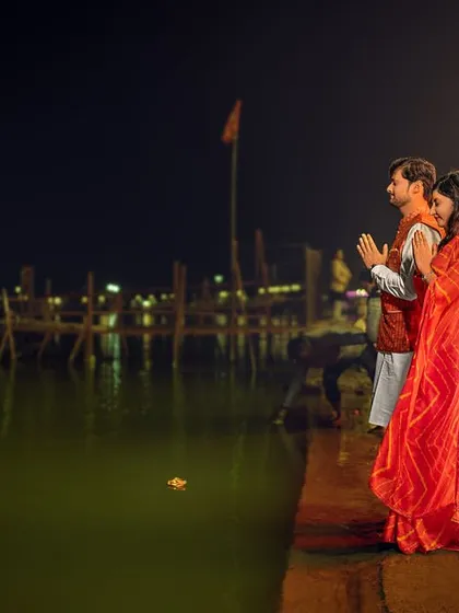 Standing at the edge of the Ganga at night, the couple offers a prayer together. The stillness of the water and the distant lights create a deeply spiritual and peaceful atmosphere for this pre-wedding shot.