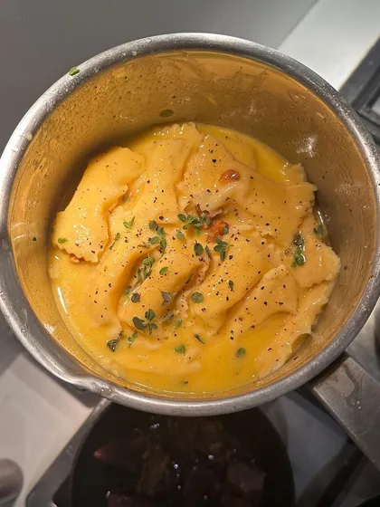 Another view of the agnolotti being finished in the pan, ensuring every piece is perfectly coated in the luscious sauce.