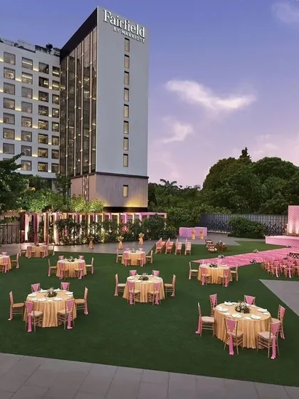 I transform open lawns into sophisticated event spaces perfect for corporate galas, client appreciation dinners, or daytime conferences. This wide-angle view shows a meticulously planned layout with coordinated table settings and a clean, professional stage backdrop against the hotel's grand architecture.