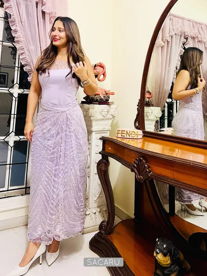 A client looking effortlessly chic in our modern cocktail ensemble, featuring a structured satin corset top and a beautifully draped skirt made from beaded lilac fabric.