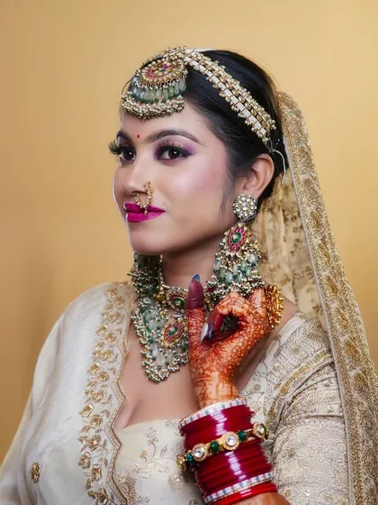 This student's bridal creation features a stunning combination of an off-white lehenga with bold, colorful jewelry, showcasing their understanding of contrast and balance.