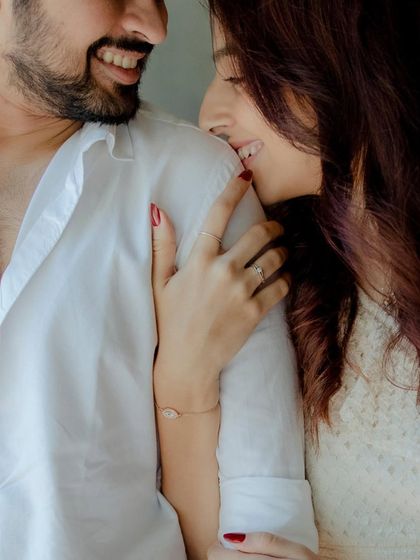 A candid and playful moment between the couple. Her gentle bite on his shoulder and their smiles show a relationship full of fun and affection.