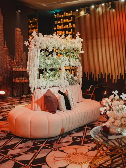 A chic lounge sofa set against a backdrop of a city skyline and a wall of flowers, providing a stylish and comfortable spot for guests to relax.