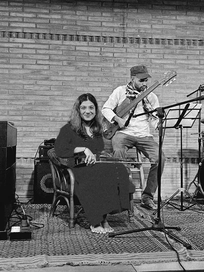A black and white photo of the REFUGE quartet, with Aman Mahajan on piano introducing a piece. The image captures the collaborative and communicative spirit of jazz.