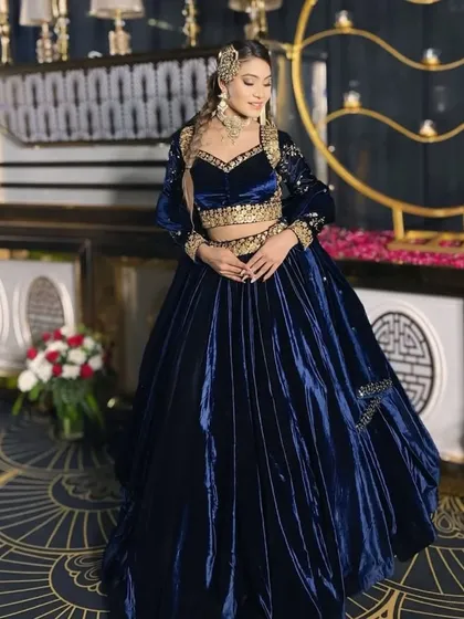A full-length shot of a model in a royal blue velvet lehenga with a jacket. This is a regal choice for a winter reception.