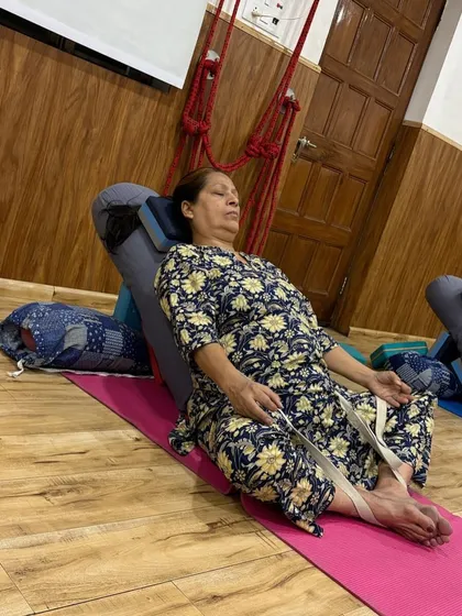 Therapy yoga often involves deep relaxation and breathwork. This student is using a bolster and strap for a supported Baddha Konasana, allowing her to relax completely.