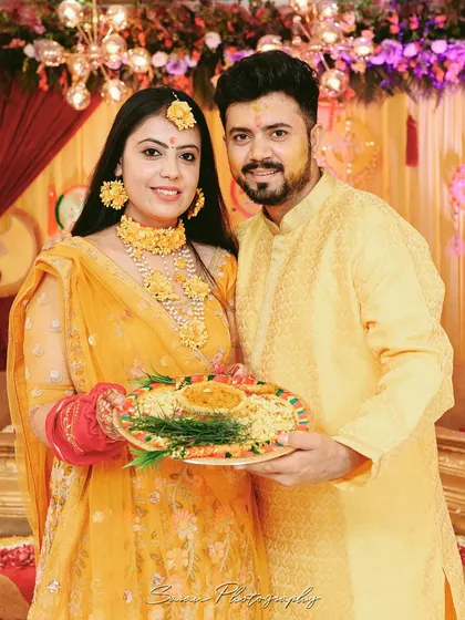 A classic portrait of the couple during their Haldi ceremony, holding a traditional plate of turmeric paste.