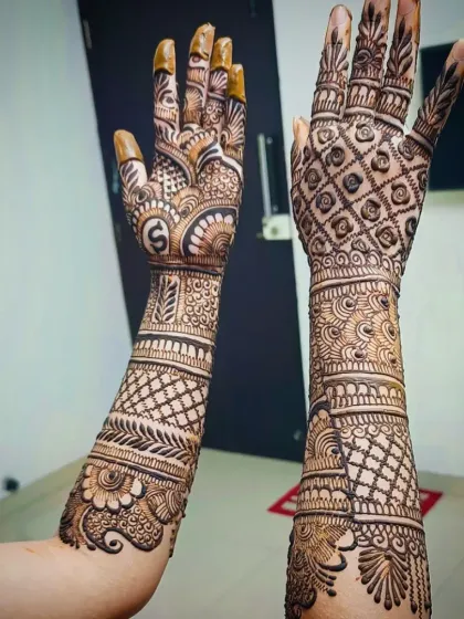 A full view of another engagement design, with the initial "S" clearly visible on one palm, surrounded by dense, traditional henna work.