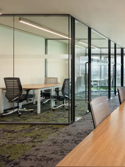 A glass-enclosed meeting room adjacent to the open work area. This design provides acoustic privacy for meetings while maintaining a visual connection to the rest of the office, fostering a sense of an open and accessible culture.