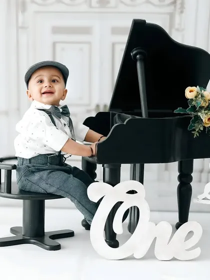 A classic and stylish first birthday portrait featuring a 'Little Pianist' theme. My studio is equipped with unique props like this miniature grand piano to make your child's milestone photos truly one of a kind.